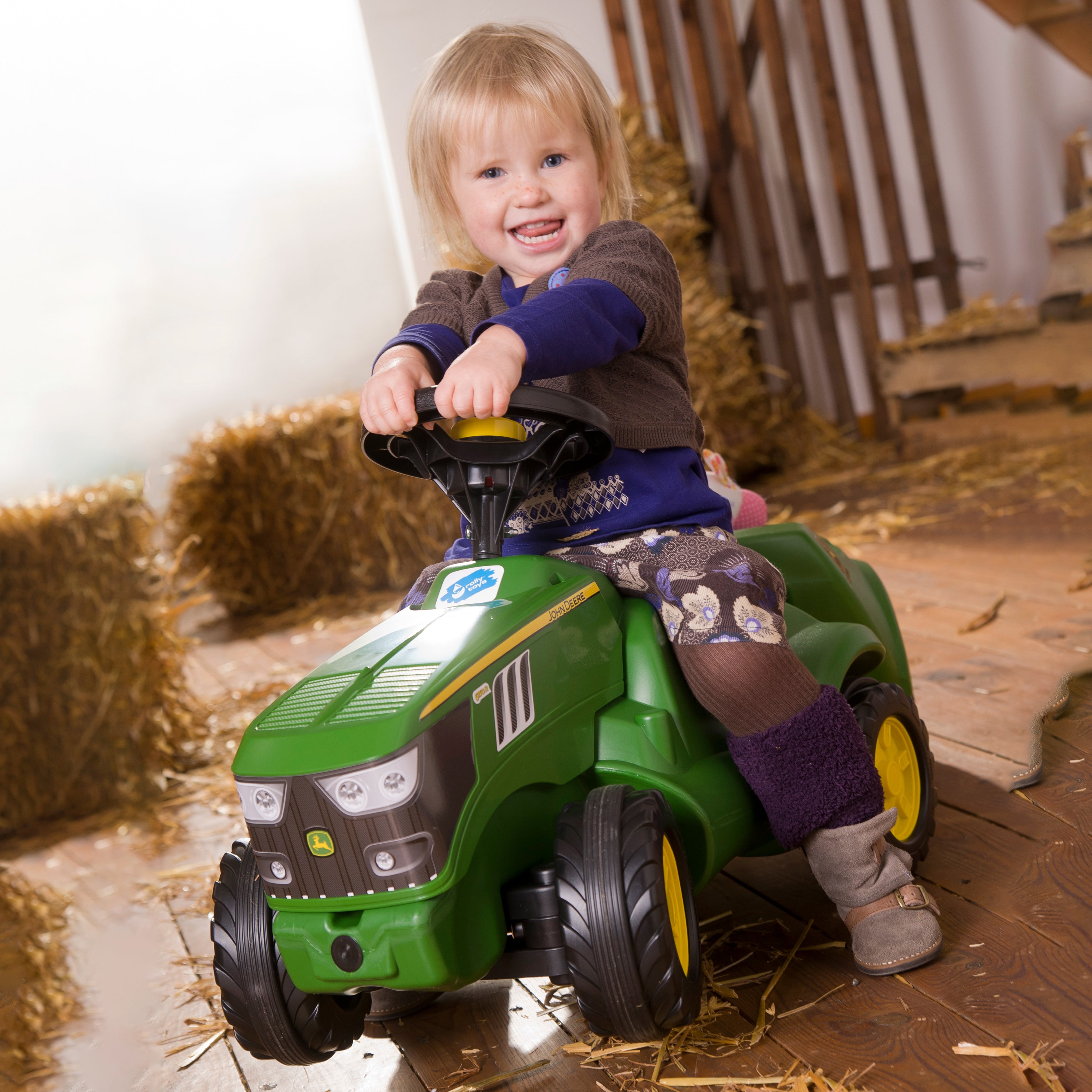 Little girl riding the John Deere Minitrac Foot to Floor Ride-On