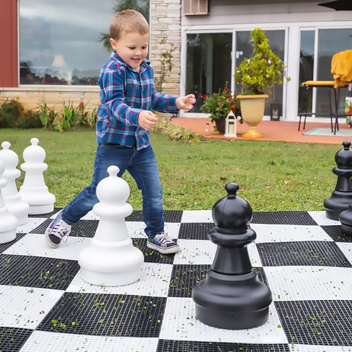Image of a yong boy playing with the giant chess set outside