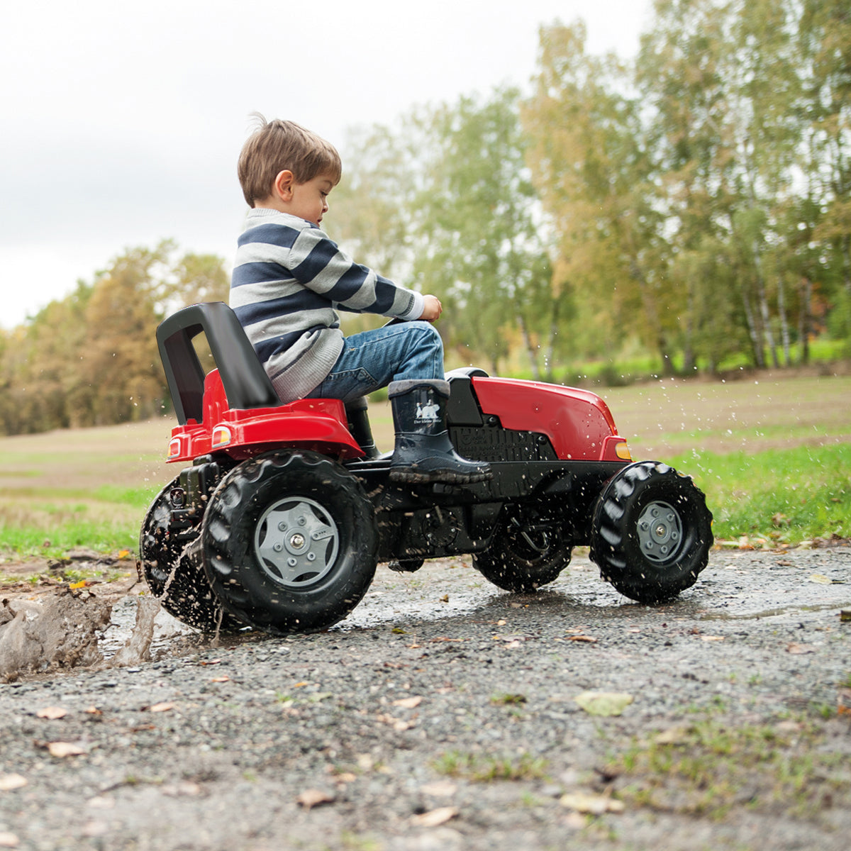 Image of a young boy riding a CASE Kid Tractor with Trailer outside