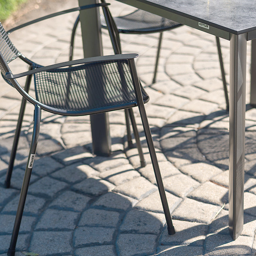 Metro 5-Piece Dining Set with stackable iron grey Metro Arm Chairs and durable 37"x37" HPL dining table outdoors.
