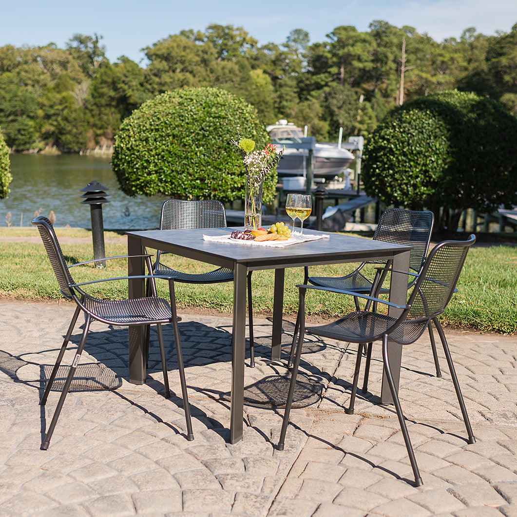 Metro 5-Piece Dining Set with iron gray arm chairs and HPL table featuring umbrella hole, perfect for outdoor use.